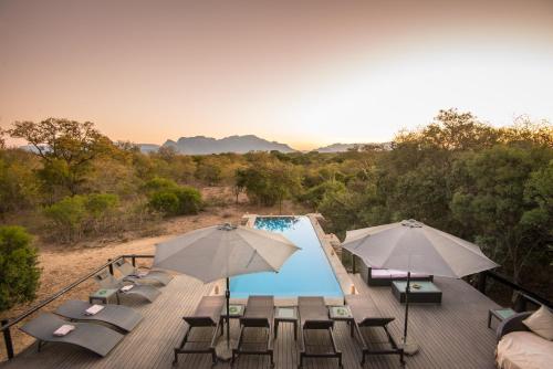 a deck with chairs and umbrellas next to a swimming pool at Vuyani Safari Lodge in Hoedspruit