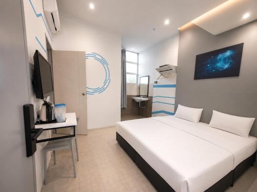 a bedroom with a white bed and a tv in it at One Stop Hotel Ipoh in Ipoh