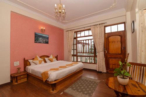 a bedroom with a bed and a table and a window at Cedar Cottage in Shimla