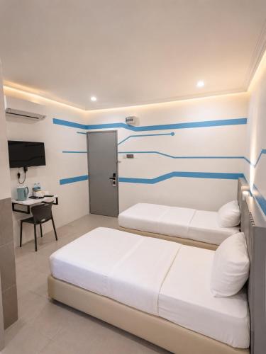a hotel room with two beds and a desk at One Stop Hotel Ipoh in Ipoh