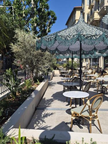 a patio with tables and chairs and an umbrella at Hotel La Villa Nice Victor Hugo in Nice