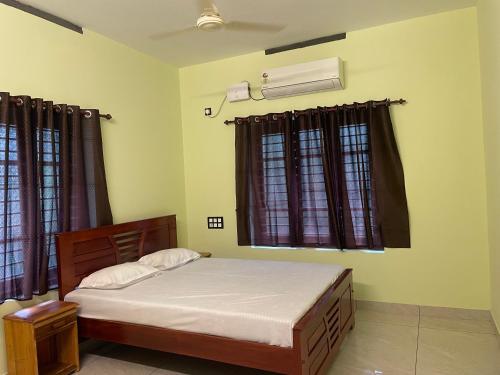 a bedroom with a bed and a air conditioner at Coz Rooms in Varkala