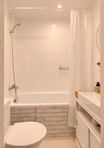 a white bathroom with a toilet and a bath tub at Narva Vibe Apartment in Narva