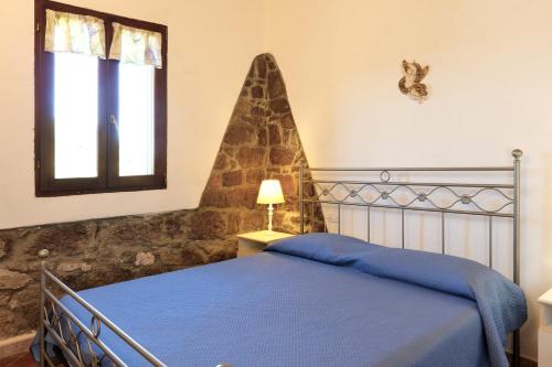a bedroom with a blue bed and a window at Salina Holiday Home in Calasetta