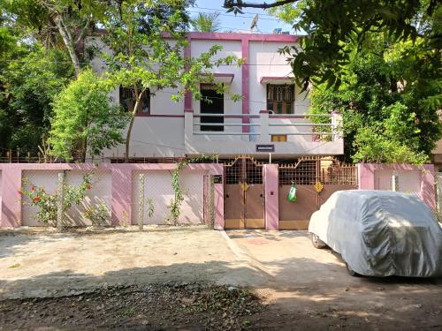 a pink house with a fence and a yard at Aiswarya illam in Chidambaram