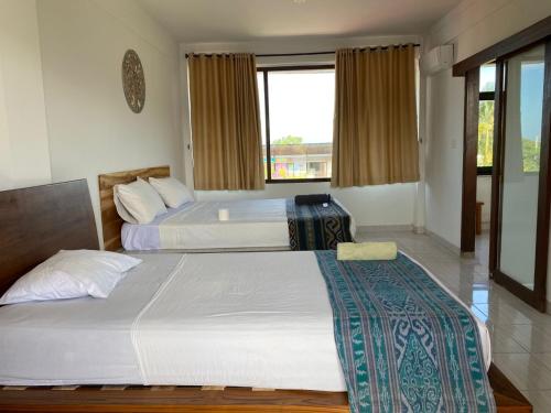 a bedroom with two beds and a window at Kutabay Homestay in Kuta Lombok