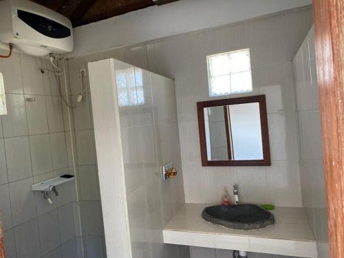 a bathroom with a sink and a mirror and a shower at Kutabay Homestay in Kuta Lombok