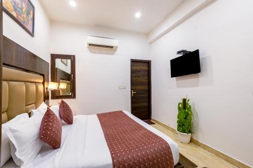 a bedroom with a bed and a flat screen tv at Hotel Kiara - Near Delhi Airport in New Delhi
