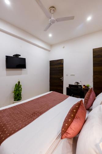 a bedroom with a bed with a television on the wall at Hotel Kiara - Near Delhi Airport in New Delhi