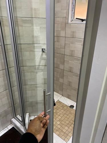 a person opening a shower door in a bathroom at Green Whisper BnB in Umtali