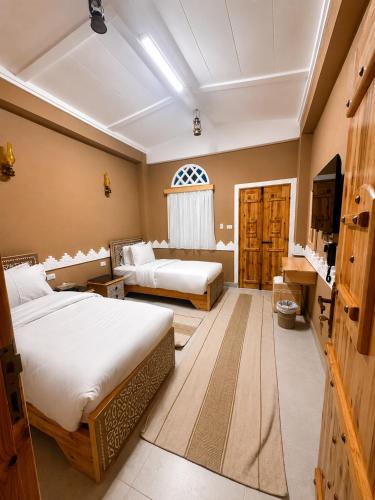 a hotel room with two beds and a television at Happy Oasis Hotel in Siwa