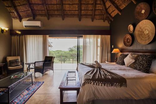 a bedroom with a large bed and a large window at Sable Ranch Thaba Khaya Lodge in Brits