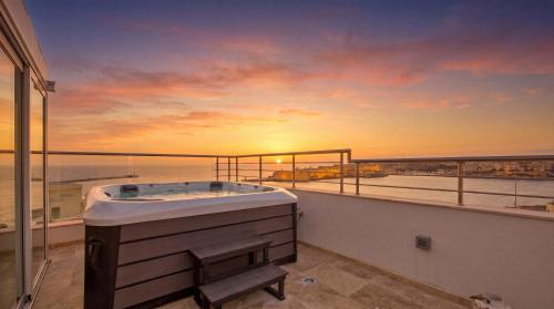 a bath tub on a balcony with a view of the ocean at Valletta Luxury 4-Bedroom Duplex with Stunning Sea Views Private Terrace and Jacuzzi in Valletta