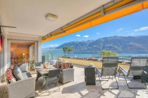 a patio with a table and chairs and mountains at Panorama Maggiore Apartment with Pool in Locarno - Happy Rentals in Locarno