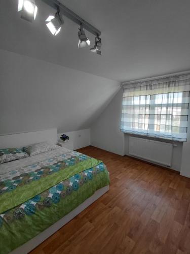 a bedroom with a bed with a green comforter and two windows at Apartment Robin in Karlovy Vary
