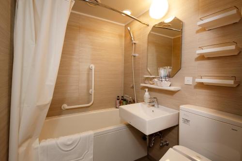 a bathroom with a sink and a toilet and a shower at Hotel Monterey Himeji in Himeji
