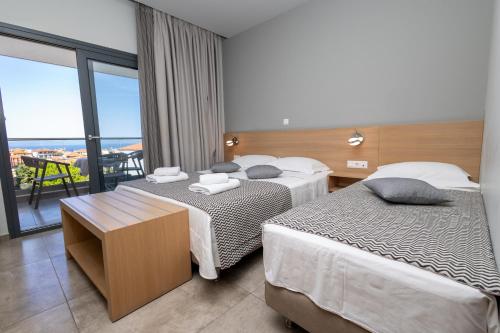 a hotel room with two beds and a balcony at Filoxenia Studios in Afitos