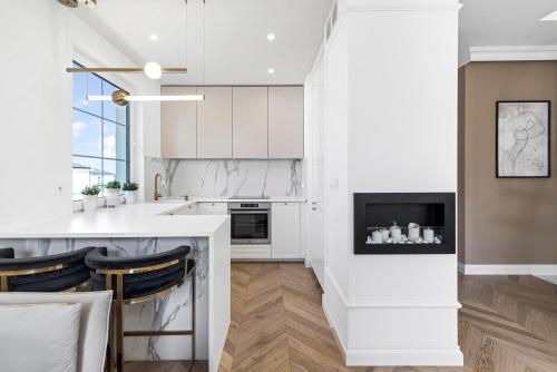 a kitchen with white cabinets and a fireplace at Tesoro Dolce Vita Apartment in Pogórze