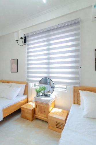 a bedroom with two beds and a mirror and a window at Chichi Inn Hotel CoTo in Đảo Cô Tô