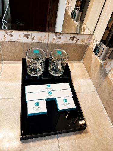 a black table with two glasses and two certificates at Cakra Kusuma Hotel in Yogyakarta