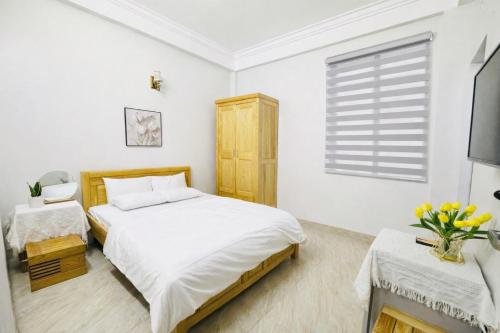 a white bedroom with a bed and a window at Chichi Inn Hotel CoTo in Đảo Cô Tô