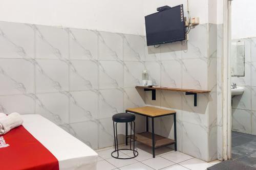 a room with a bed and a stool and a tv at RedDoorz at Hotel AVA Malioboro in Jetis