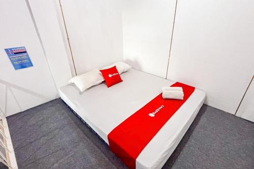 a small bed in a room with red and white pillows at RedDoorz at Hotel AVA Malioboro in Jetis