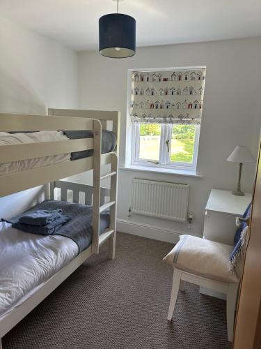 a bedroom with two bunk beds and a window at Waters Reach in Abersoch