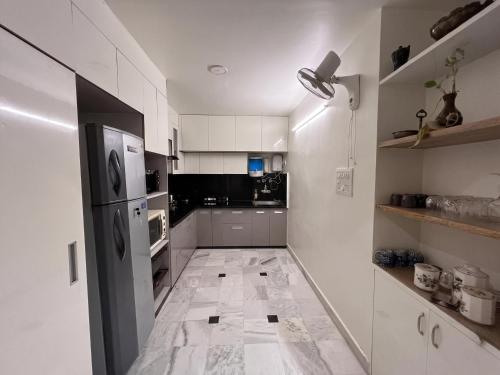 a kitchen with white cabinets and a black refrigerator at Cozy Loft 201 2 BHK in Jaipur