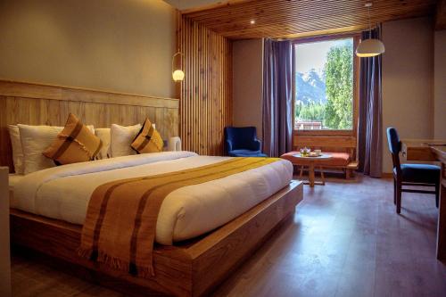 a bedroom with a bed and a desk and a window at Hotel Rewa Ladakh in Leh