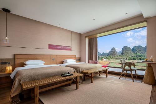 two beds in a room with a large window at 自由鸟觅野山舍-阳朔十里画廊遇龙河店 in Yangshuo
