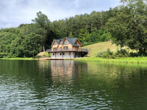 a house sitting on the edge of a lake at Stanica MODRAK - Najpiekniejszy ZAKĄTEK KASZUB in Ręboszewo