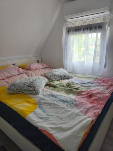 a bed with colorful sheets and pillows in a bedroom at Melba Vendégház in Dömsöd