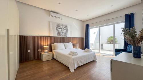 a bedroom with a white bed and a large window at Villa Ida - Indoor Heated Pool, Sauna, Games Room and Gym in Mellieħa