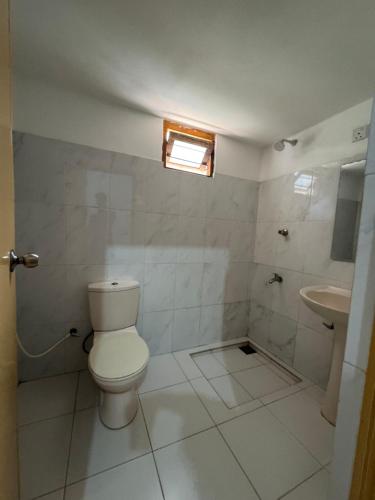a white bathroom with a toilet and a sink at Luckwin Guest in Anuradhapura