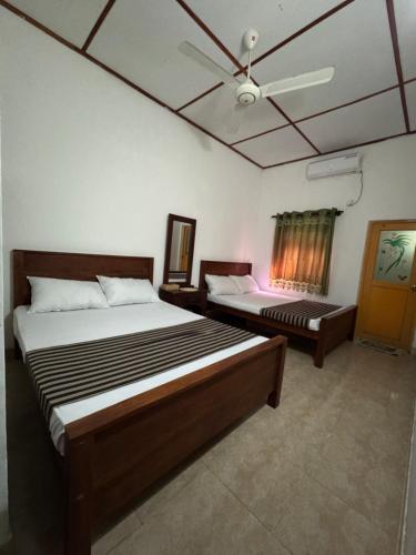 a bedroom with two beds and a ceiling fan at Luckwin Guest in Anuradhapura