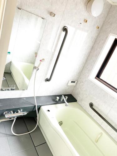 a bathroom with a bath tub and a mirror at fully in Otsu