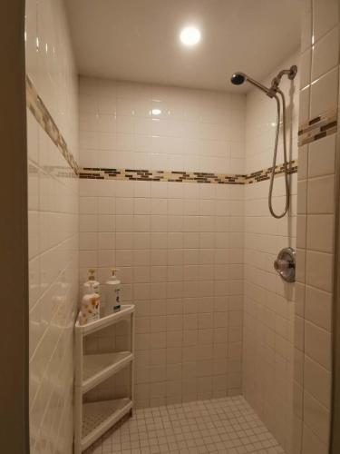 a white tiled bathroom with a shower and a sink at Love Capilano in North Vancouver