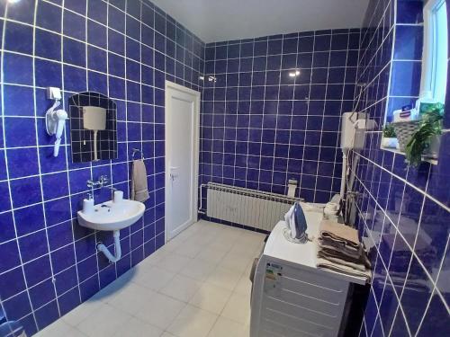 a blue tiled bathroom with a sink and a toilet at OAZA Miokus in Miokus