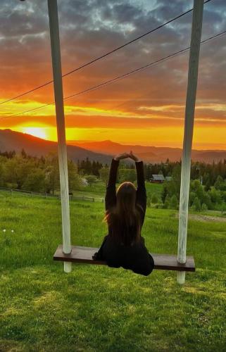 a woman sitting on a swing watching the sunset at Hutsul Glamp Панорамний вид Джакузі Best Sunset in Mykulychyn