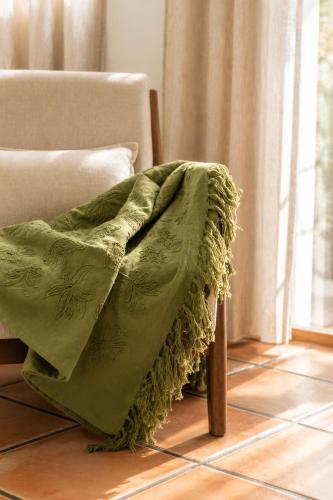 a green blanket on a chair in a room at Alojamientos El Cañico in Moratalla
