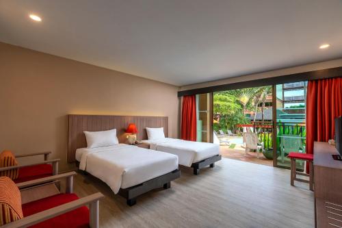 a hotel room with two beds and a balcony at Kata Sea Breeze Resort - SHA Plus in Kata Beach
