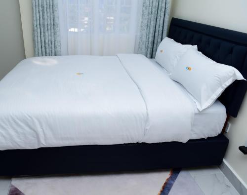 a bed with white sheets and pillows in a room at comfystdngong in Nairobi