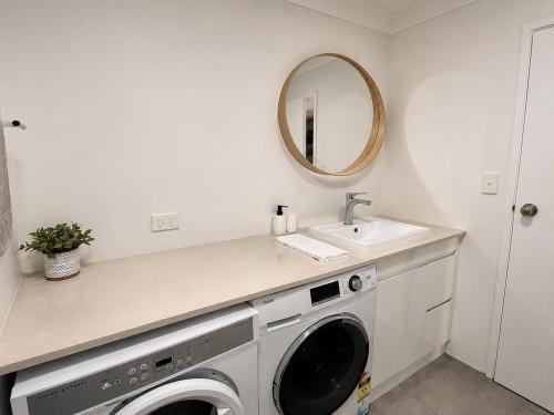 a white laundry room with a sink and a washing machine at West Beach Lagoon 123 - Location & Views!!! in Perth
