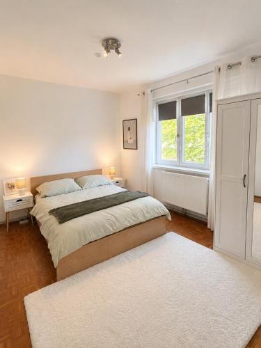 a white bedroom with a large bed and a window at Helena City Apartment in Leoben