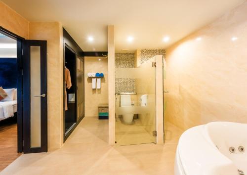a bathroom with a tub and a toilet and a sink at Kata Sea Breeze Resort - SHA Plus in Kata Beach