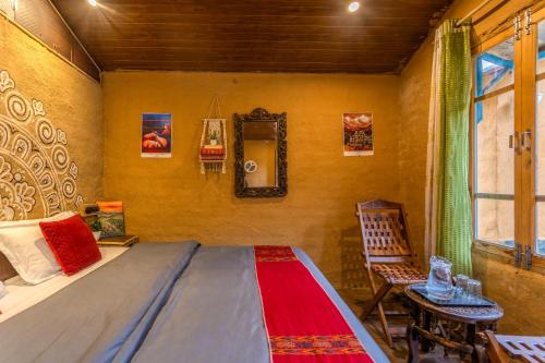 a bedroom with a bed and a table and a chair at Monkey Mud House and Glamps, Bir in Bīr
