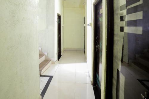 an empty hallway with a white floor and a door at Hotel O Celebrity in Chandrapur