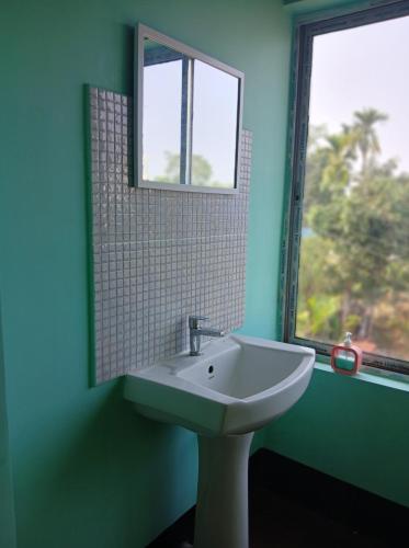 a bathroom with a sink and a mirror and a window at sicsac inn in Jorhat