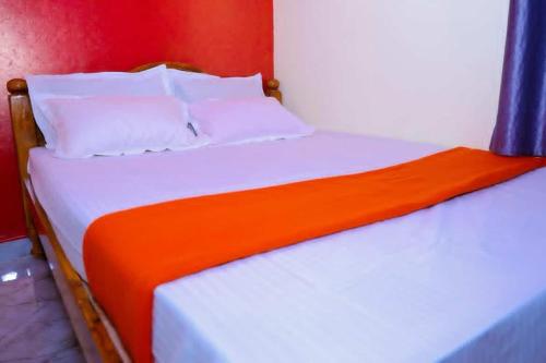 a bed with an orange and white blanket on it at Loki guest House in Chikmagalūr